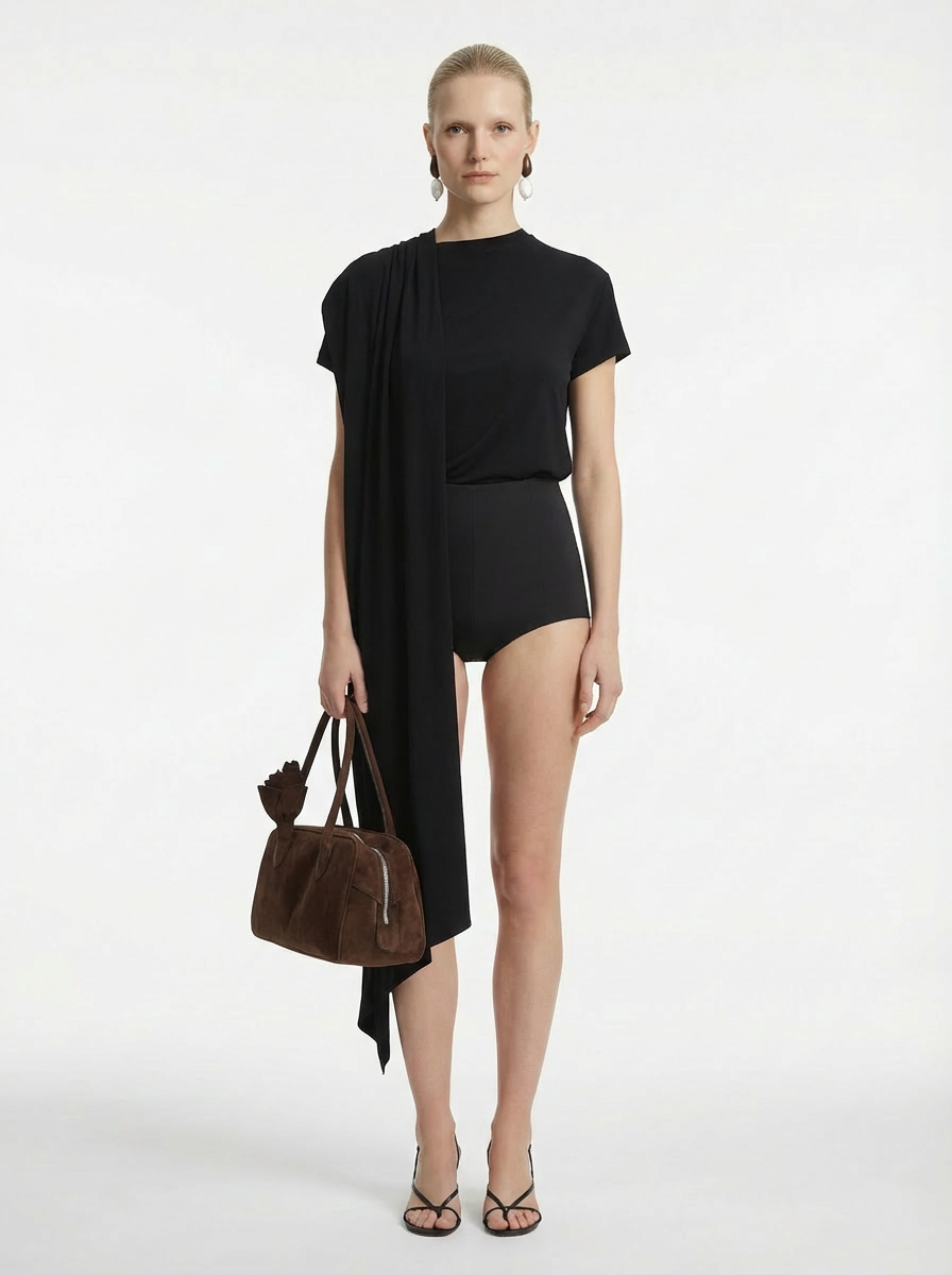 Woman wearing a black outfit with a brown handbag on a white background