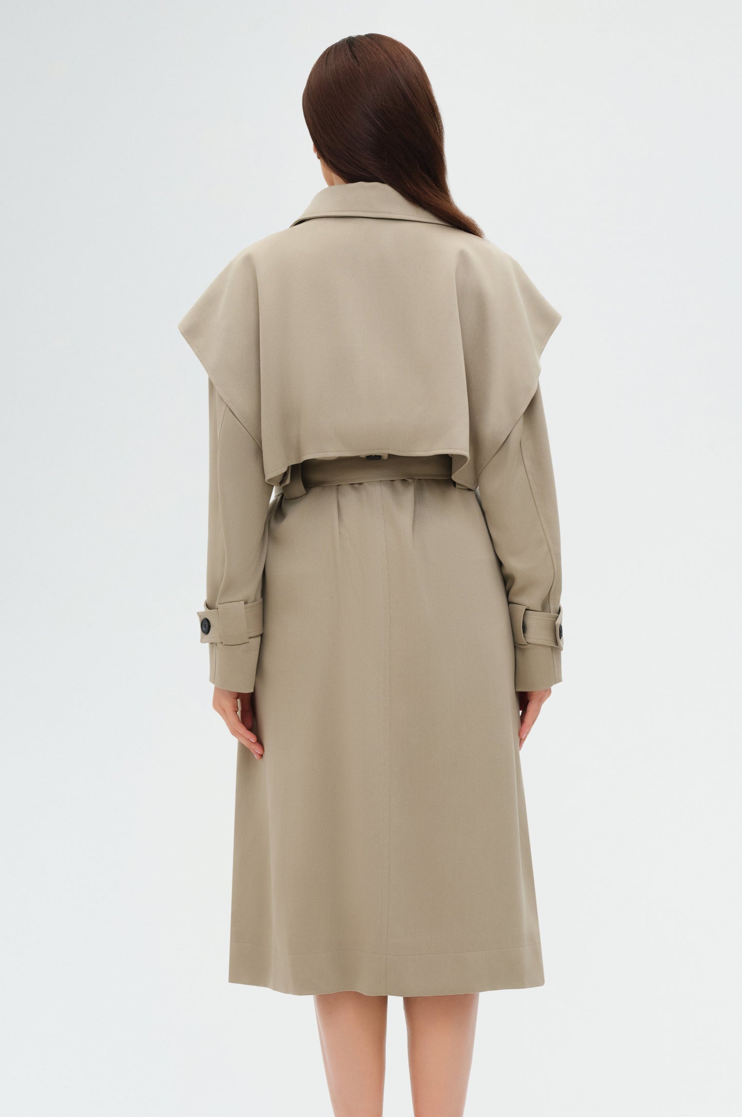 Person wearing a beige trench coat on a white background