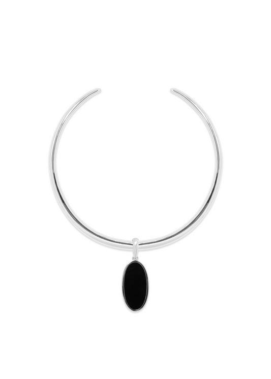 A minimalist silver-toned metal cuff bracelet with a small, vertically oriented oval black stone pendant, shown against a plain white background.