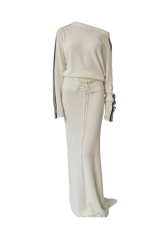 An off-the-shoulder knit maxi dress in cream with black stripe details down the sleeves and a matching lace-up waist belt, shown on a white background.