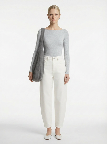 Woman wearing a gray sweater and white pants on a white background