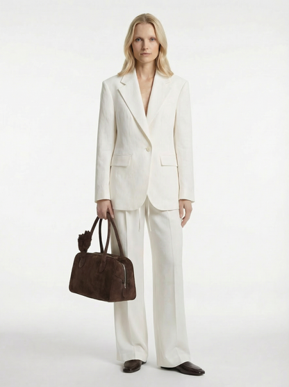 Woman in a white suit holding a brown bag on a white background