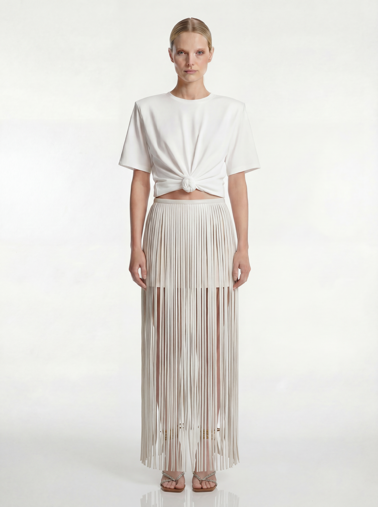 Woman wearing a white top and pleated skirt on a white background