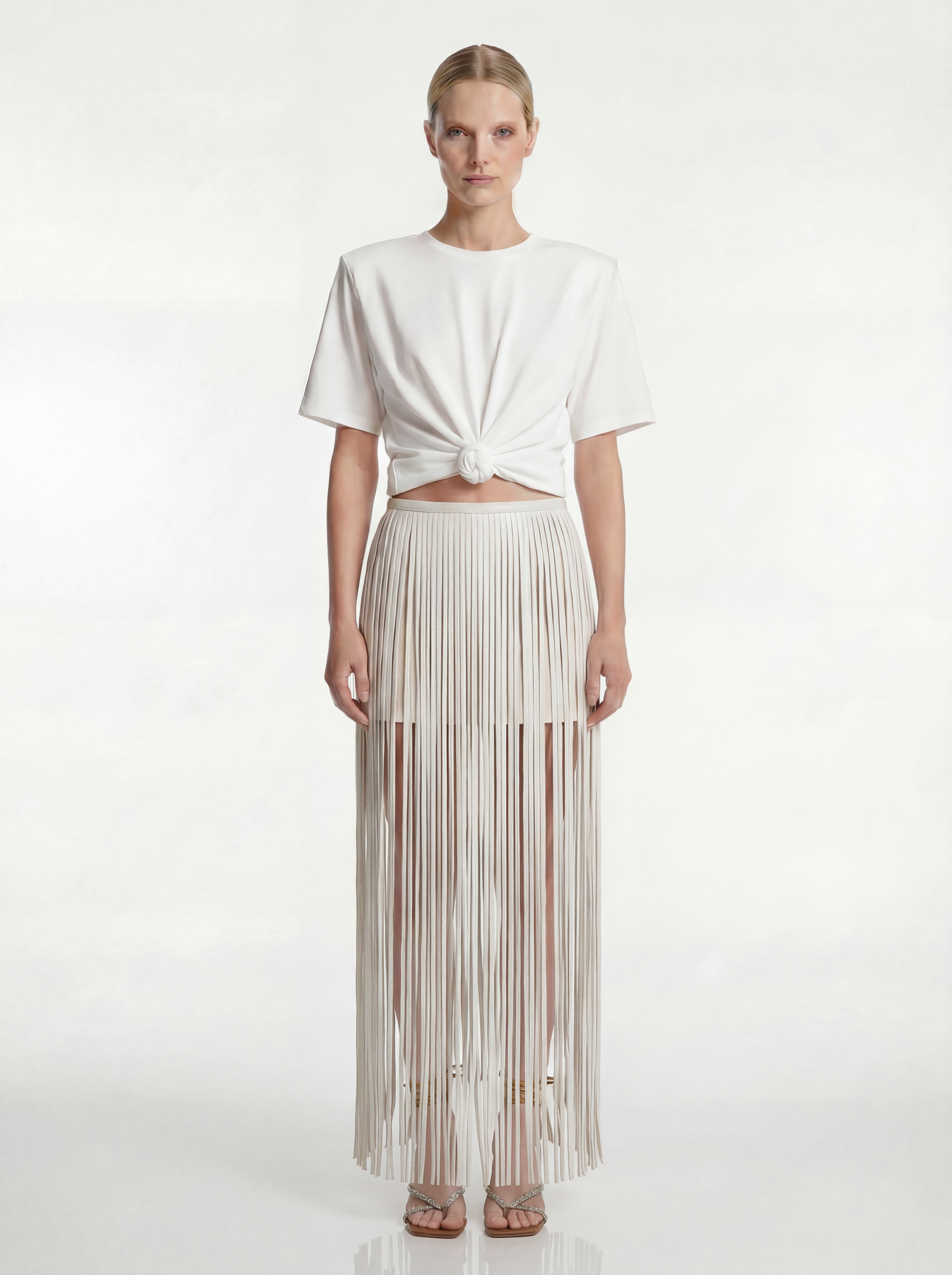 Woman wearing a white top and pleated skirt on a white background