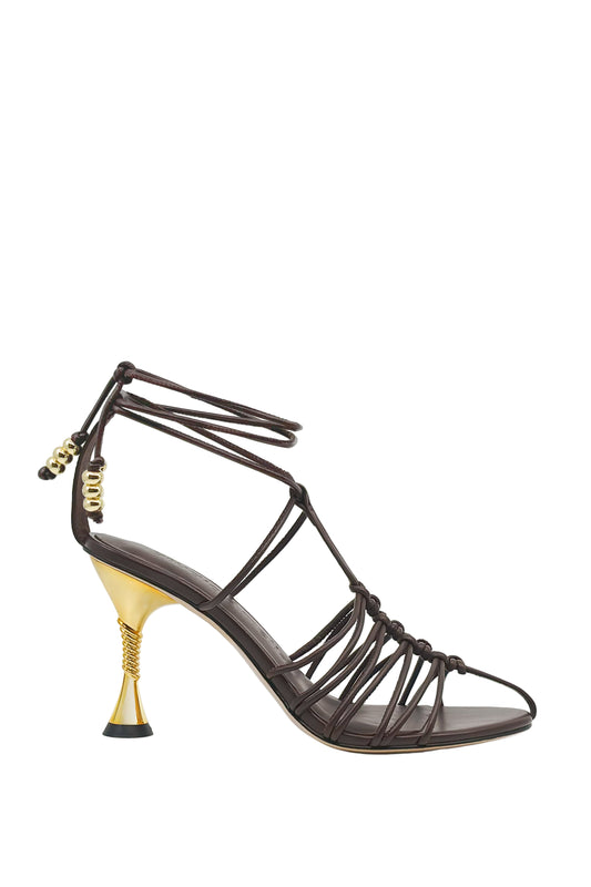 Black strappy high-heeled shoe with gold heel on a white background