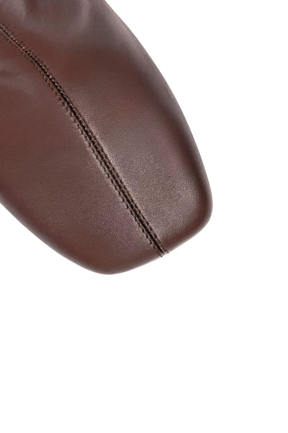 Close-up of a brown leather seat with visible stitching on a white background
