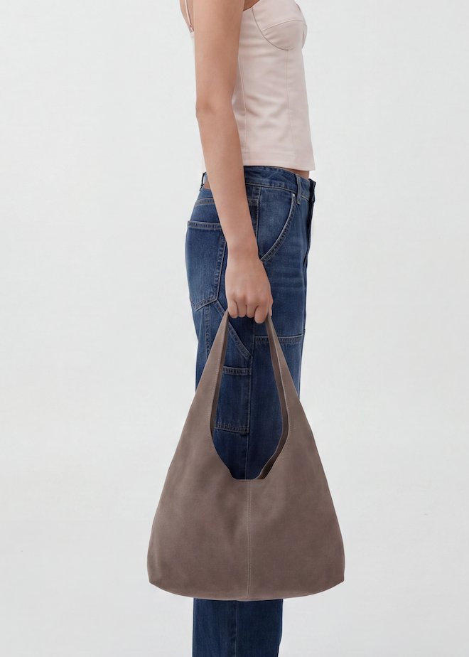Person holding a gray tote bag against a plain background